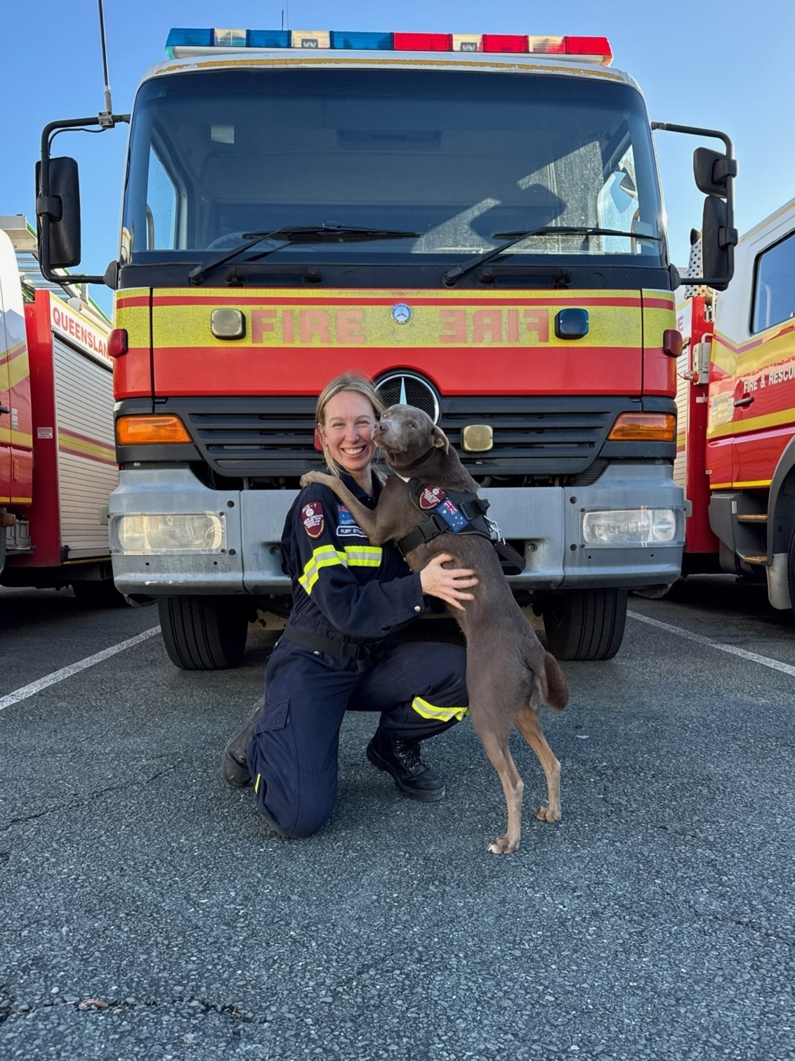 Ruby stands in front of a fire truck holding her dog.
